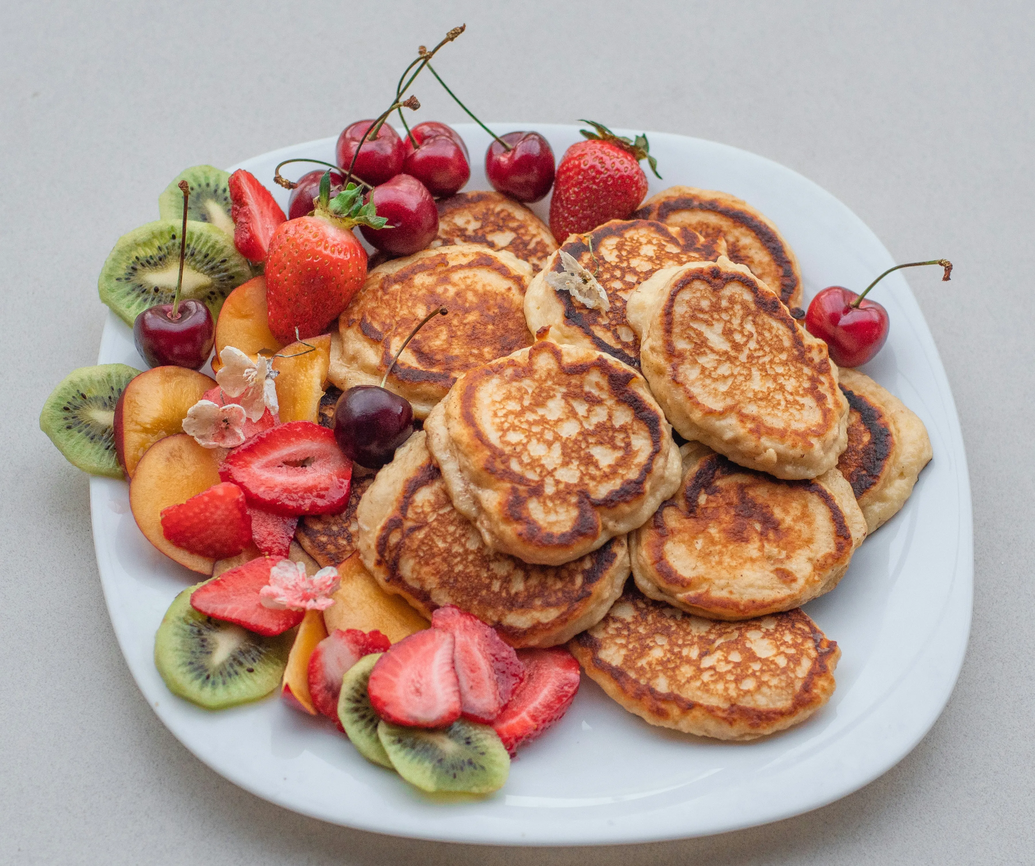 Plate of golden pancakes served with fresh fruit at Fluff and Crunch pancake and waffle house in Warman, SK